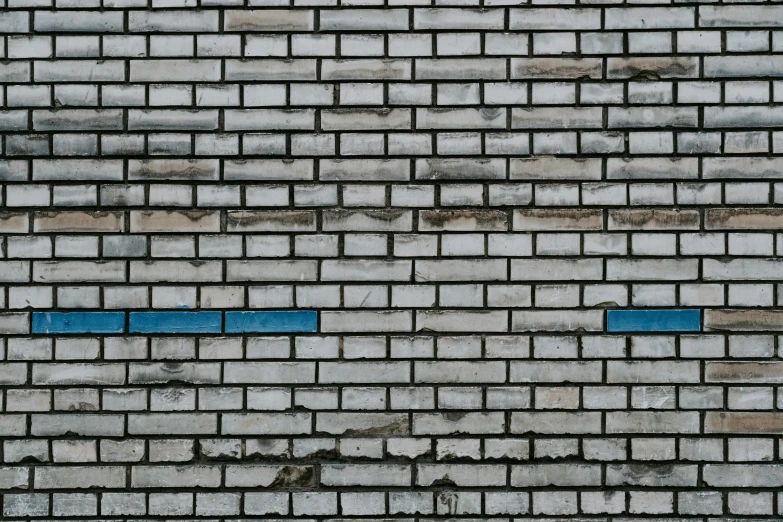 a blue brick wall has an overlaid sign on it