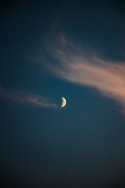 a half moon is seen against a cloudy sky