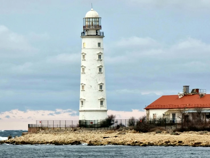 the tall white tower sits next to the water