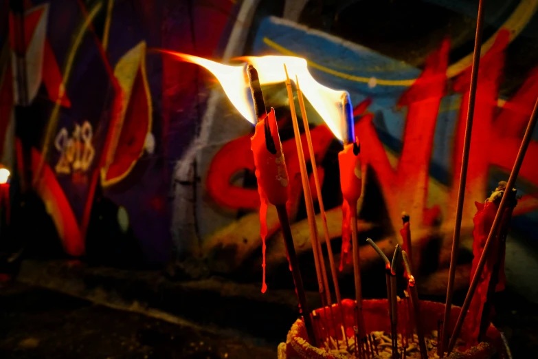 some red sticks sitting in front of graffiti