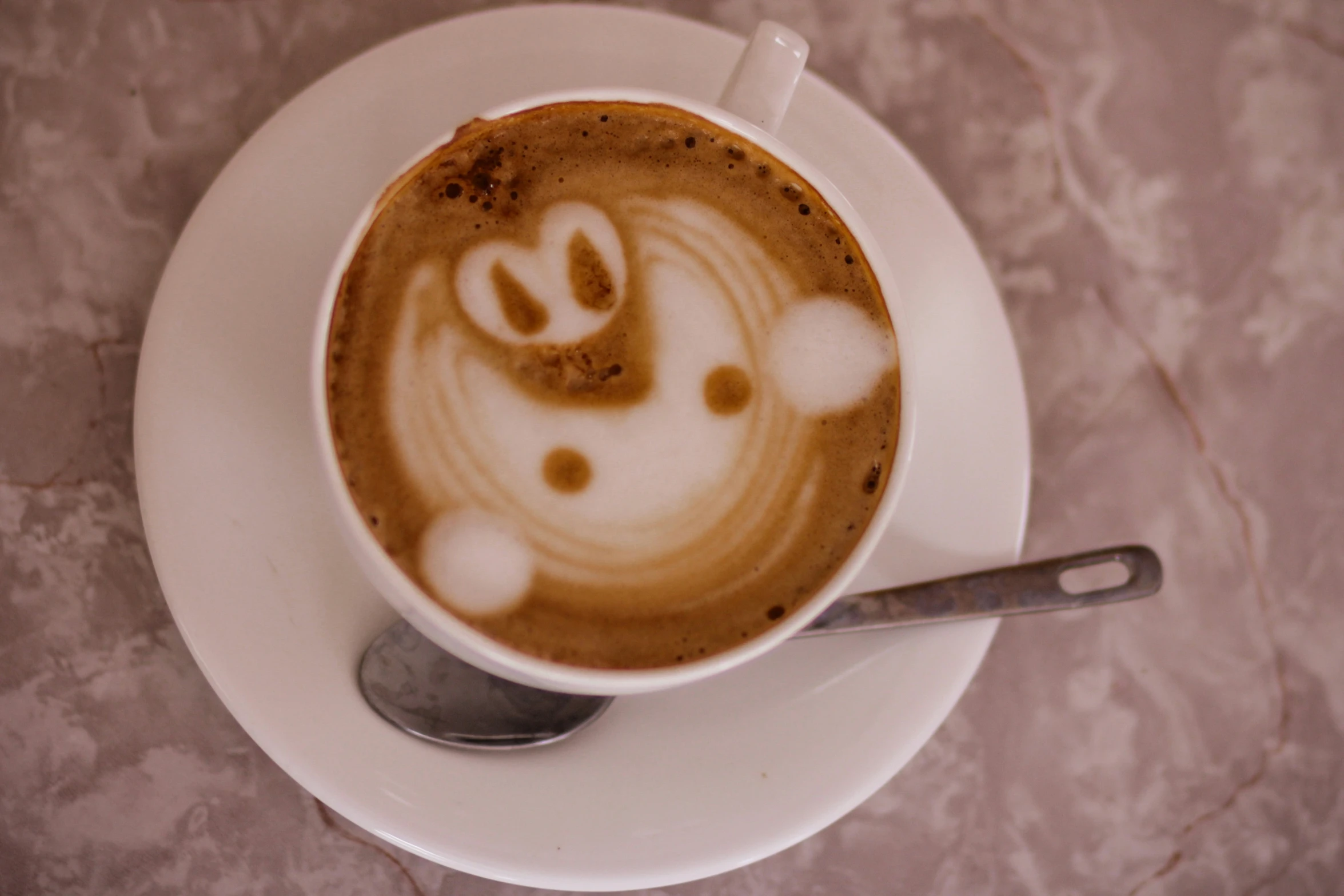 a cup of coffee with a face drawn on top