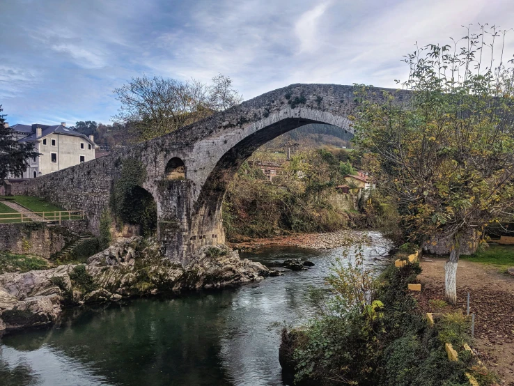 a bridge and path crossing over a stream in front of a small castle