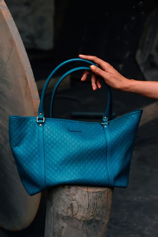 a woman holds a teal colored, hand bag