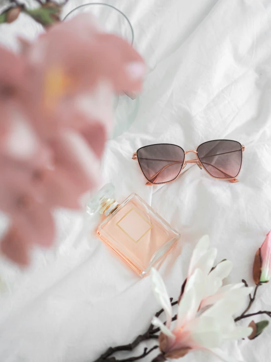 sunglasses and cosmetics laid out on a bed