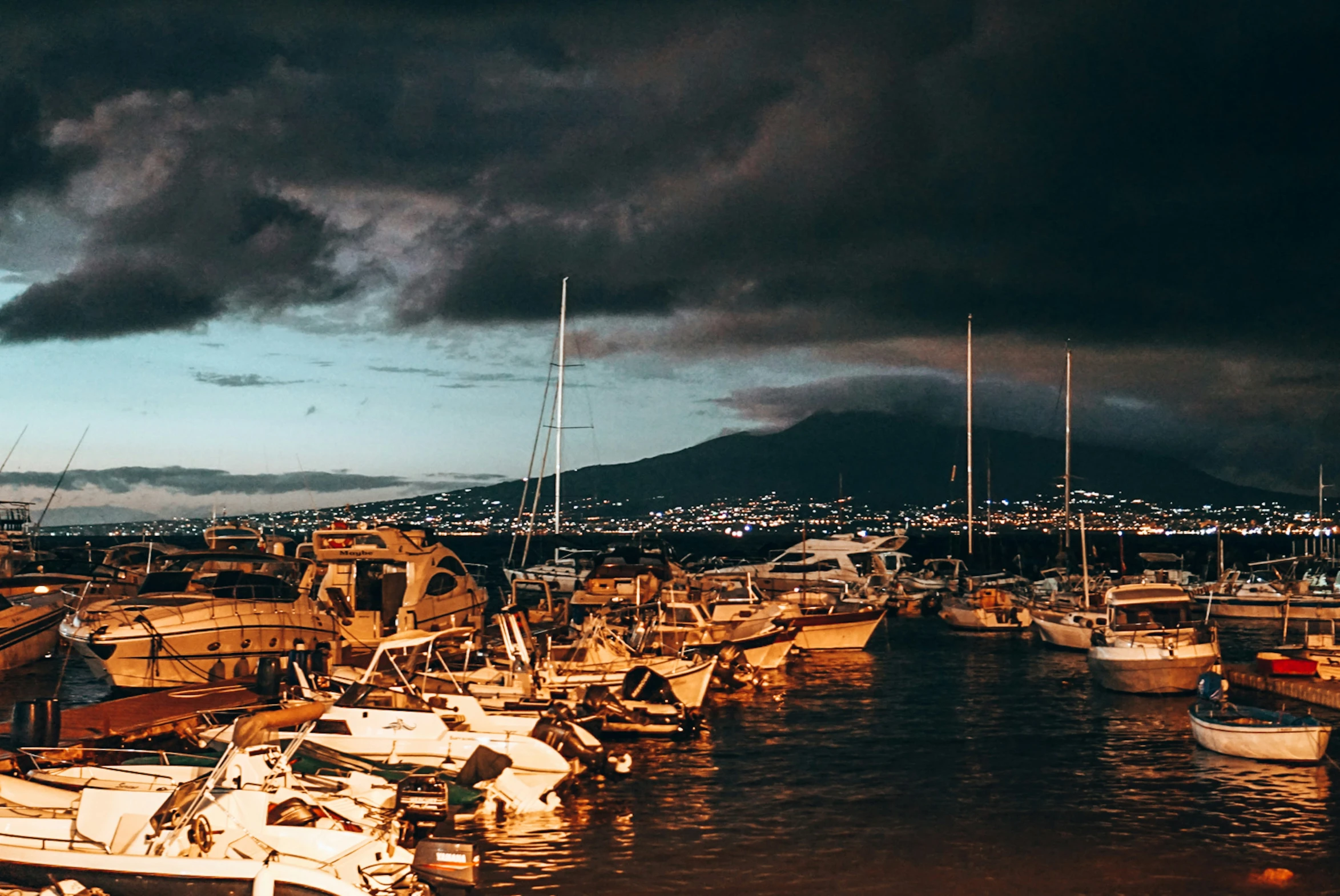 boats docked at a harbor under a cloudy sky