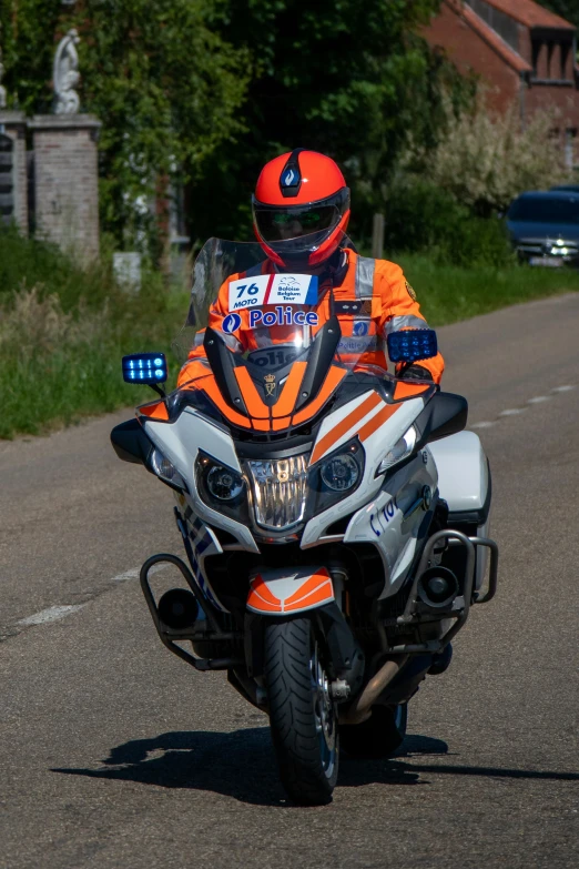 an orange motorcycle rider is turning while driving down a road