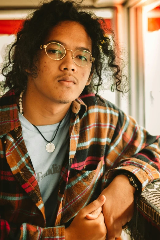 a man with glasses sitting down next to a wall