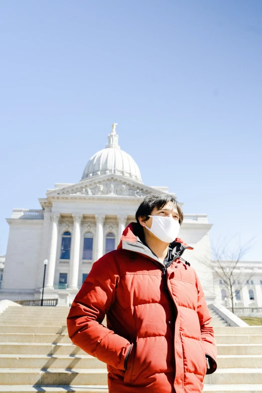 a man wearing a face mask stands in front of a building