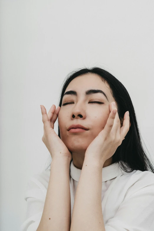 a woman with her eyes closed and both of her hands on her head