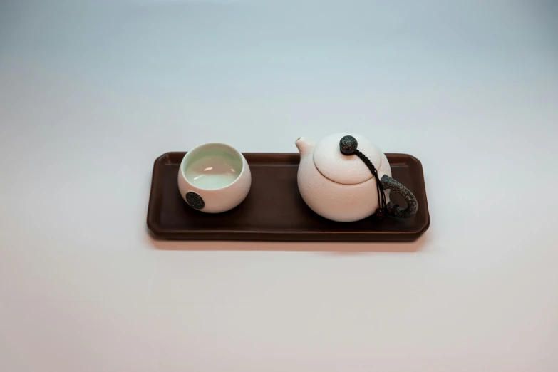 a set of two white tea pots and one has an asian style handle