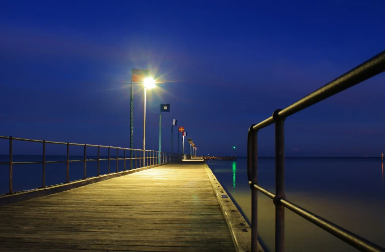 a pier on the water with a light and a street lamp