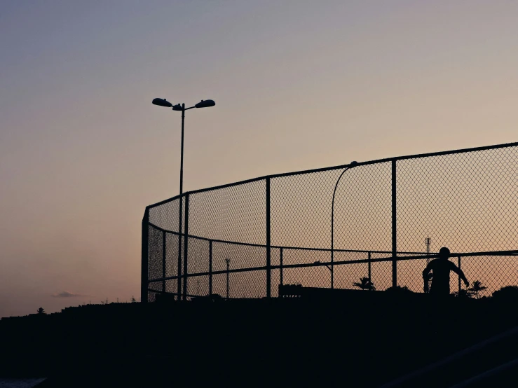 a man stands outside behind an industrial fence