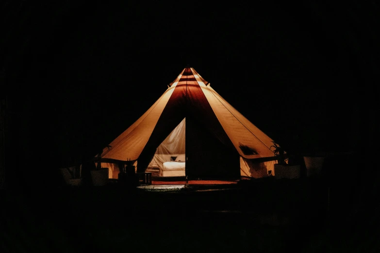 a tent is lit up in the dark by a street light