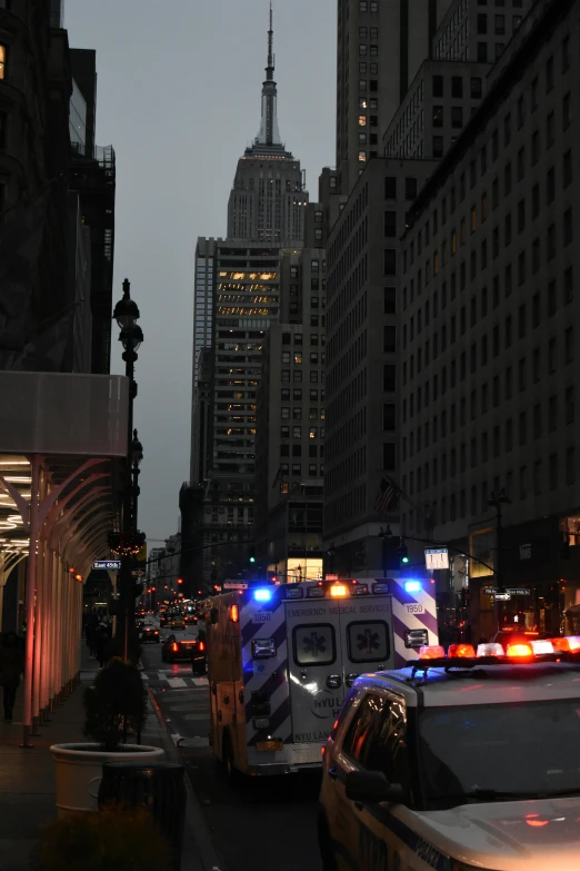 emergency vehicles traveling down a street next to tall buildings