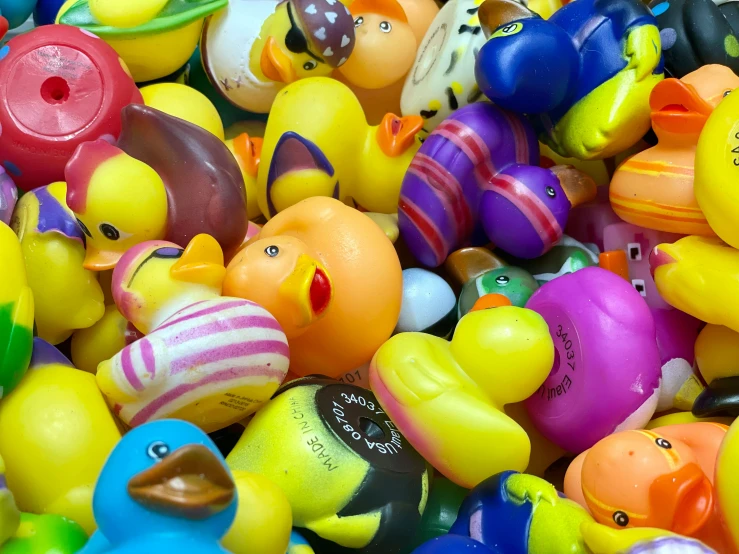 a pile of rubber ducks with yellow, orange, green, blue and pink colors