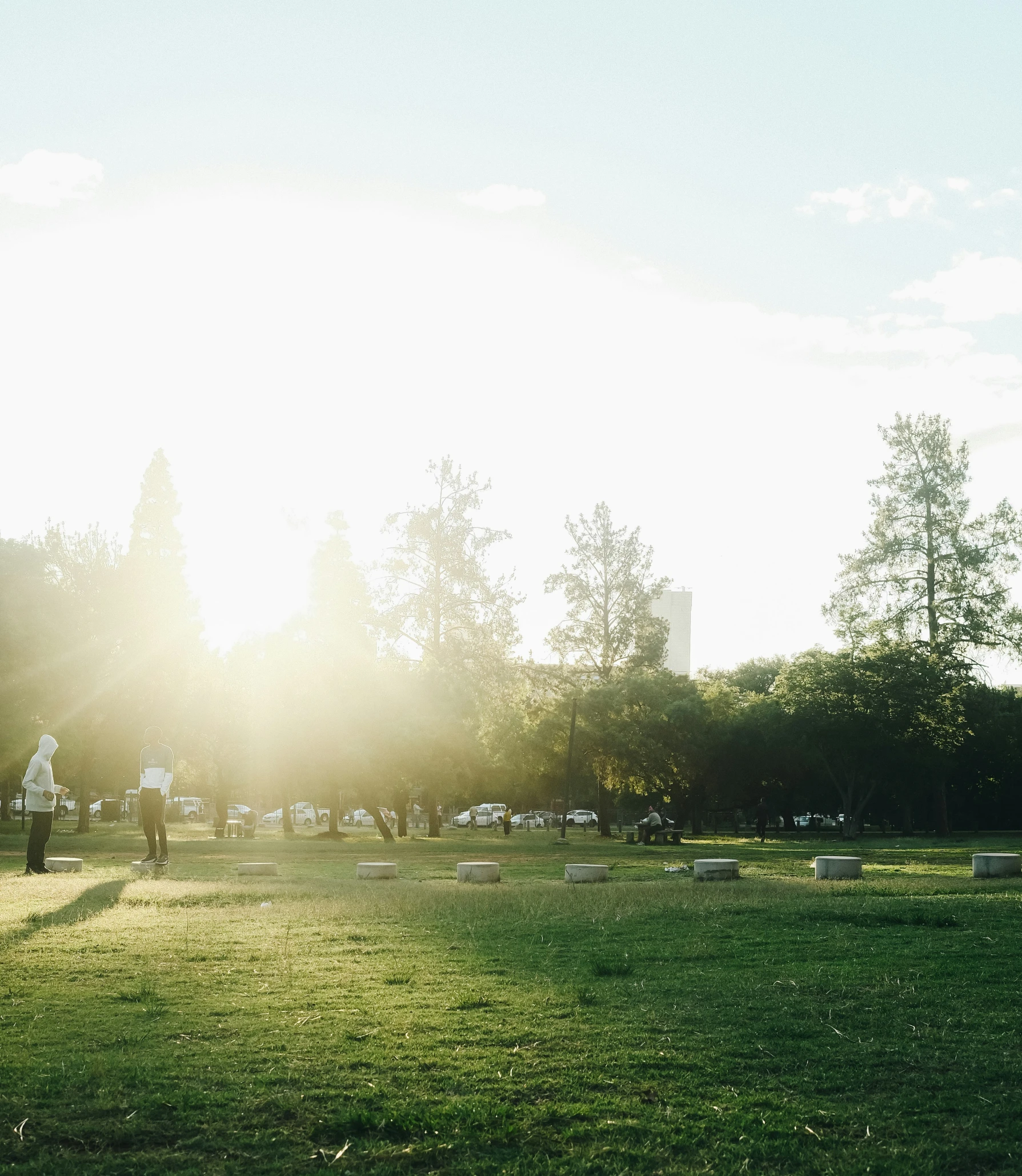 the sun is shining down on some people playing frisbee