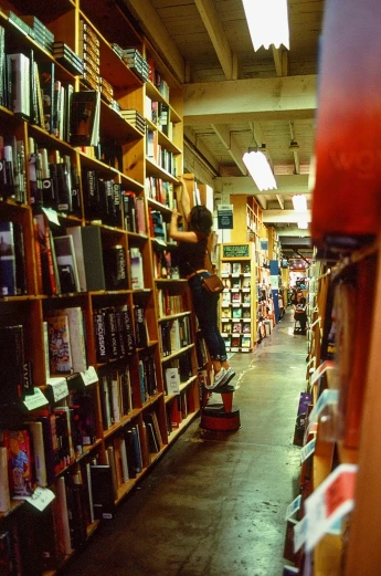 there is someone standing on the bookshelf in a bookstore