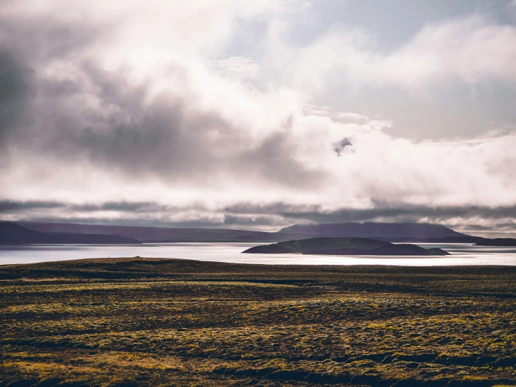 clouds over a body of water and an island on land