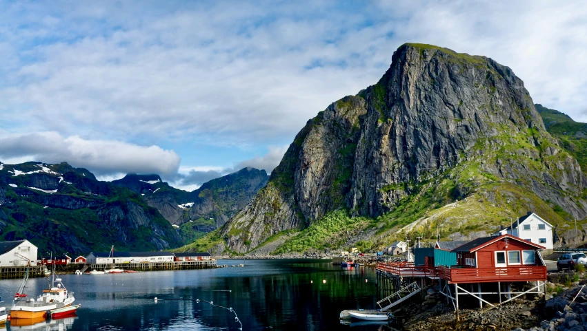 boats are docked at a small marina below the mountains