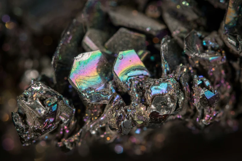 a cluster of rainbow colored diamonds next to some black rocks