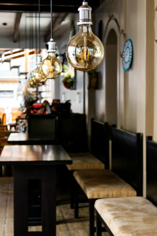 a restaurant with wooden benches, and hanging lights