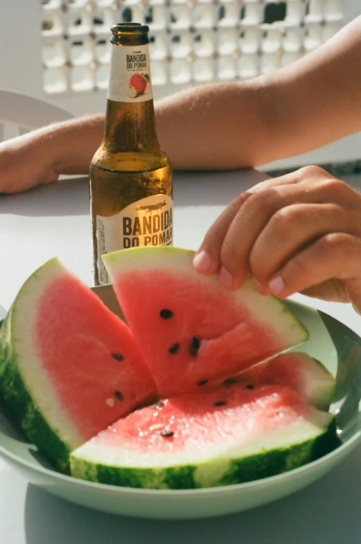 a person holding a piece of watermelon on a plate with two other pieces of watermelon on the plate