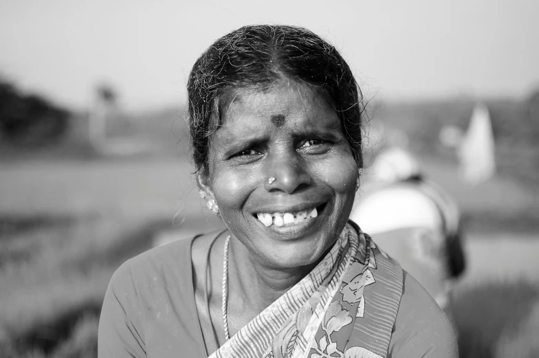 a woman standing in a field smiling for the camera