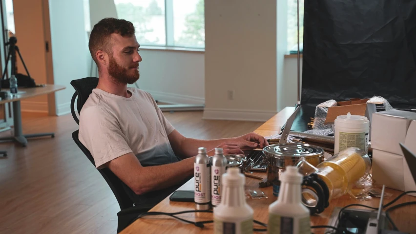 a bearded man sits in a chair on the computer