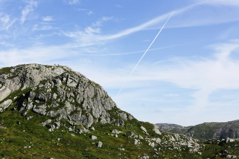 an airplane is flying over a grassy mountain