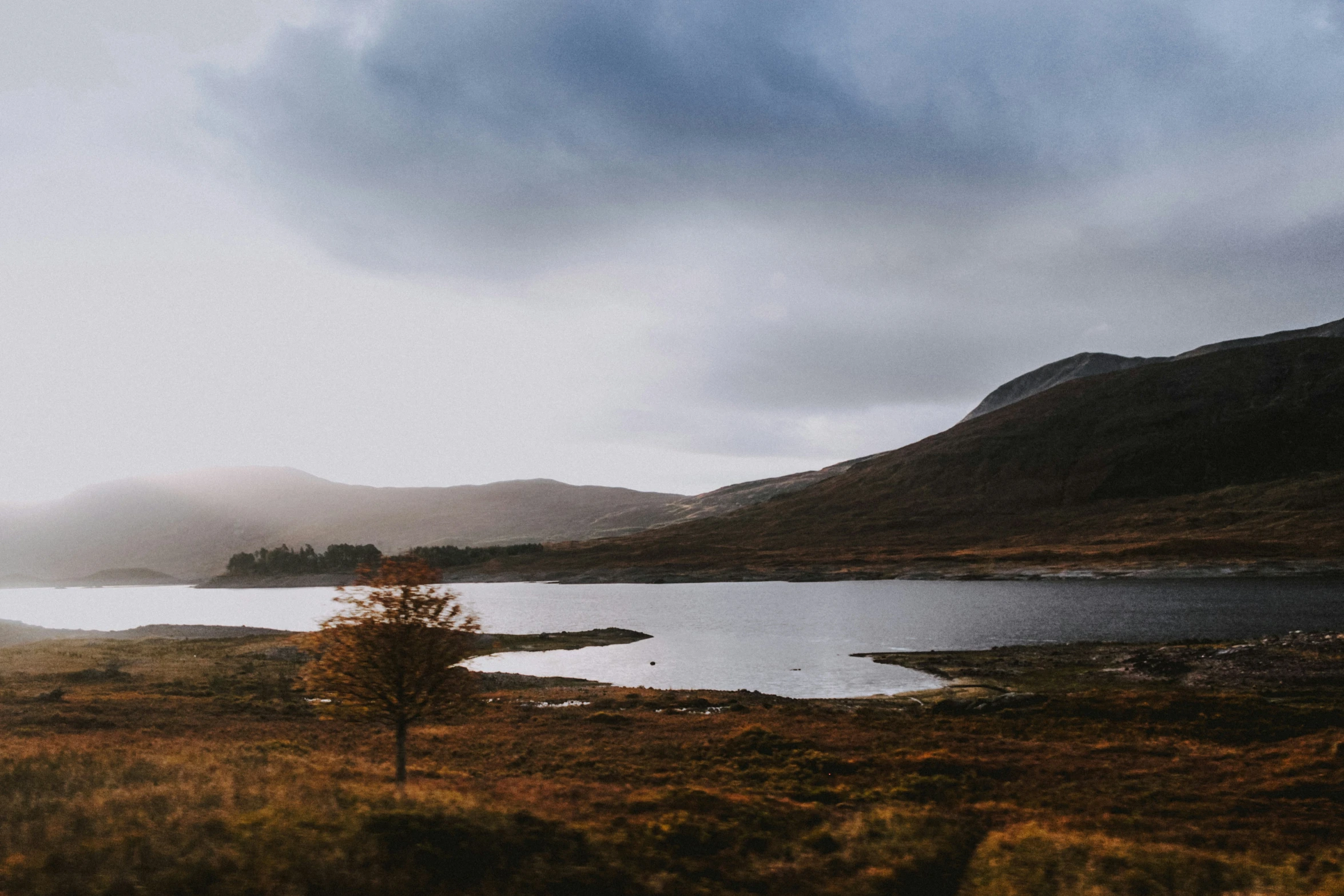 a body of water surrounded by lush green hills