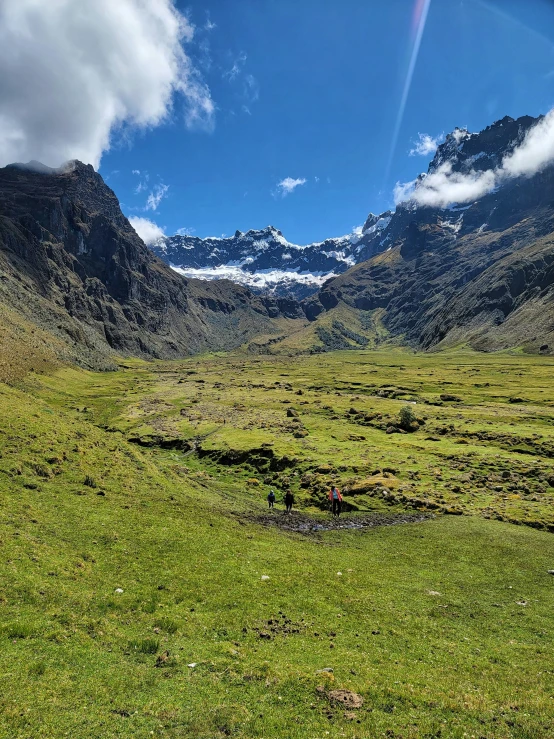 a mountain range with green grass and mountains in the background