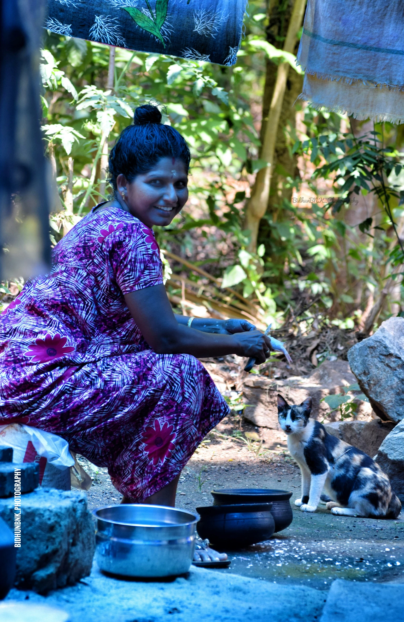 woman sitting on ground with cats near her