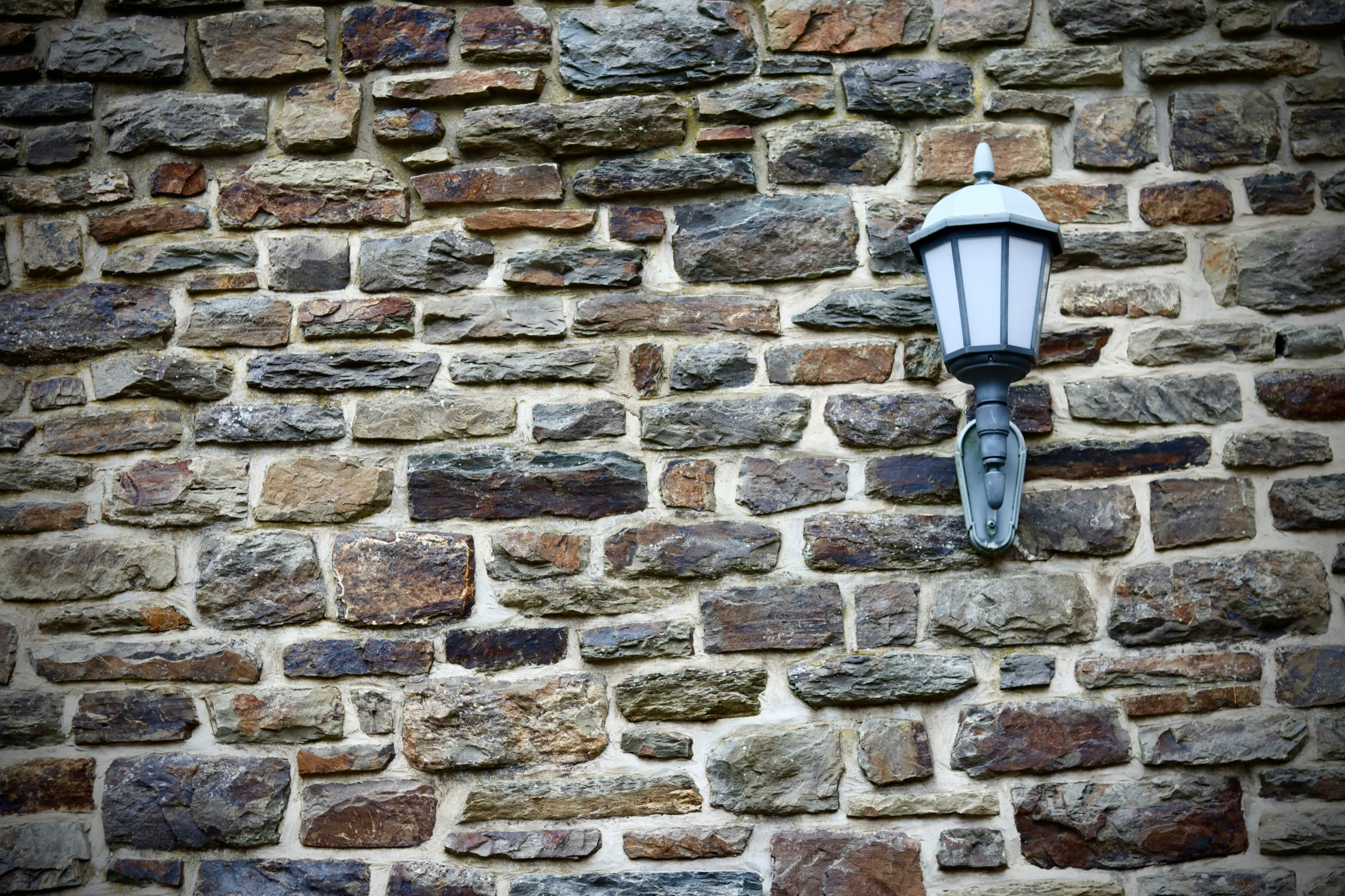 a lamp that is on the side of a brick wall