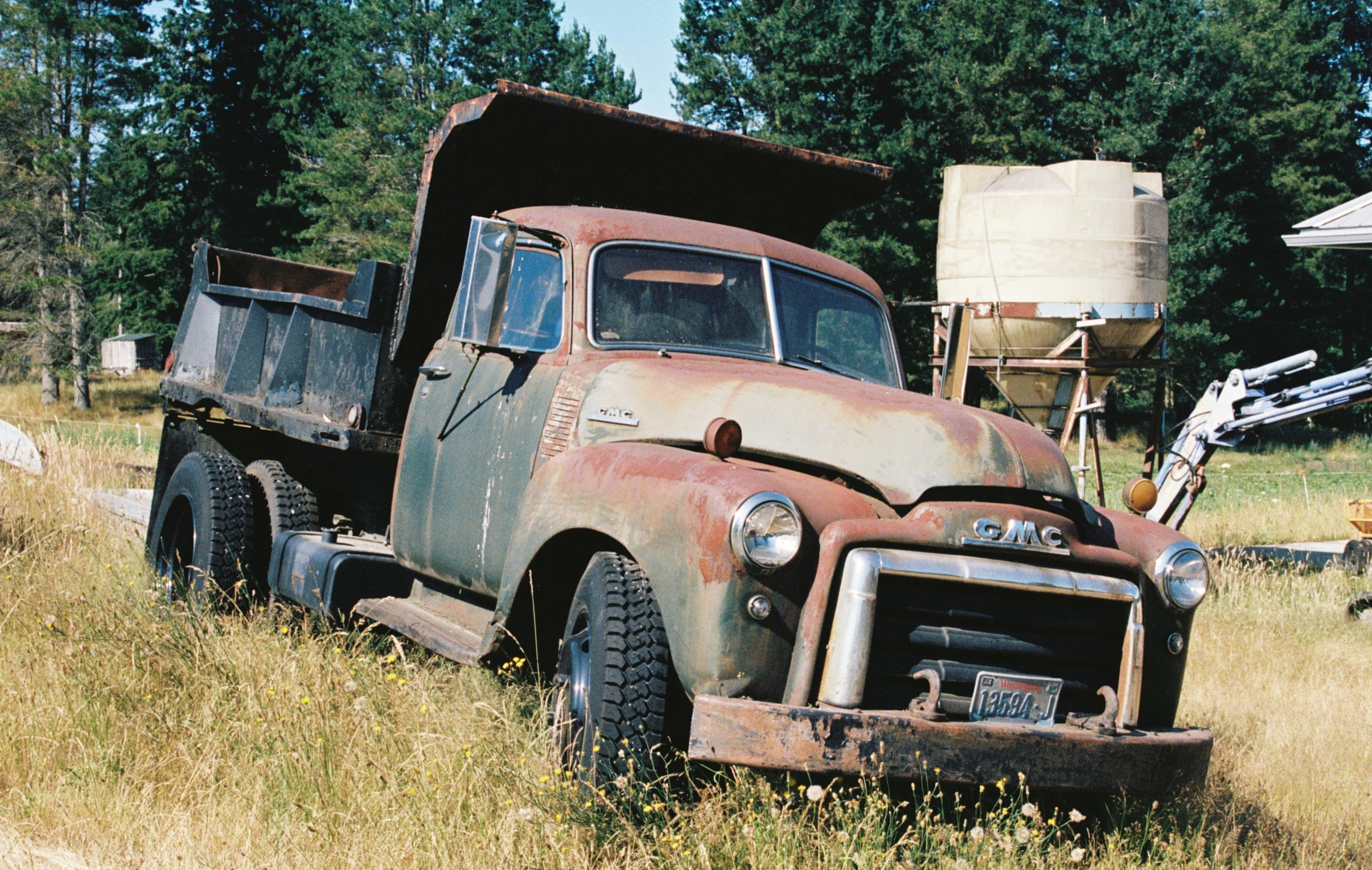 an old truck in a field with trees and dirt