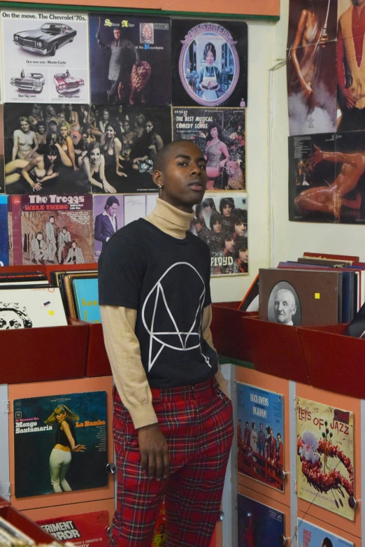 a man wearing plaid pants stands by a record shop