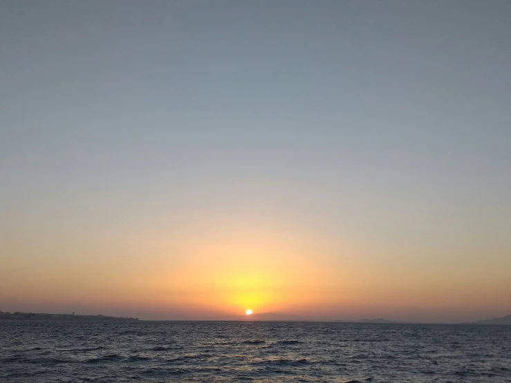 a bright orange sun setting over the ocean