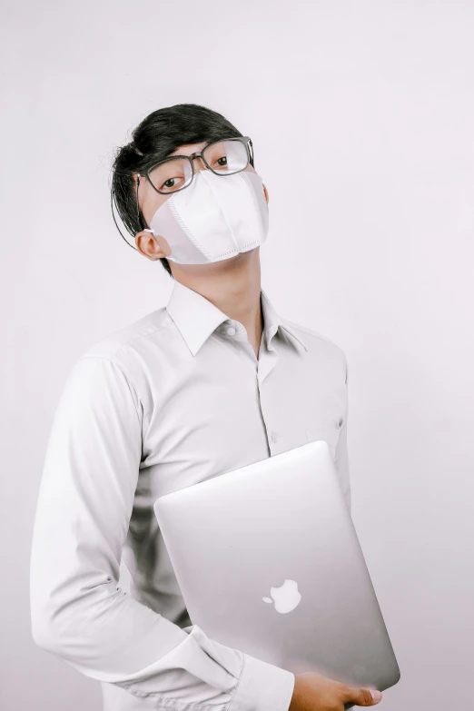 a man wearing a face mask and holding a laptop