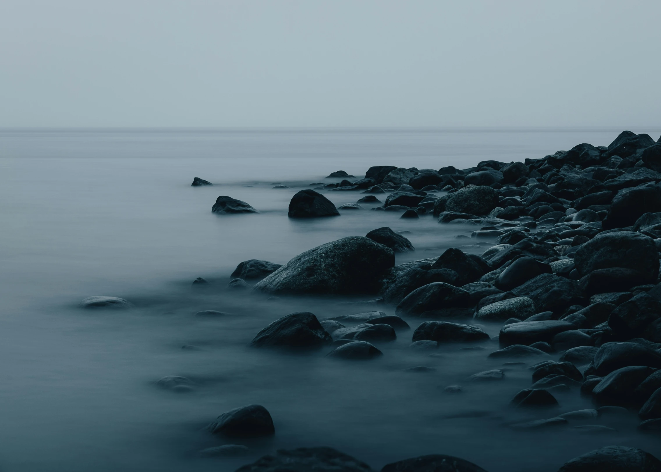 black and white pograph of rocks near the ocean