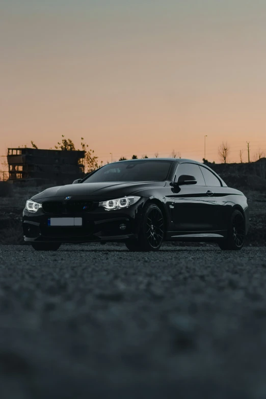 a black car with the sun setting in the background