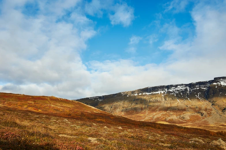 a hill with snow covered summit under a blue cloudy sky