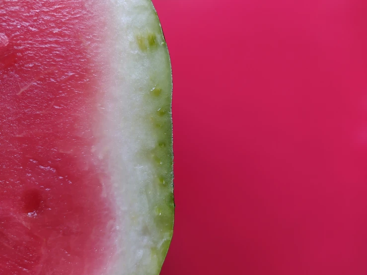 a watermelon slice and a piece of it on a pink background