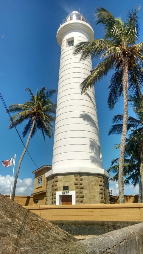 a white light house is on display under the trees