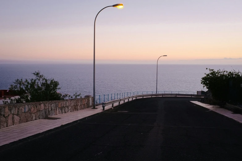 an empty street with streetlights near the water