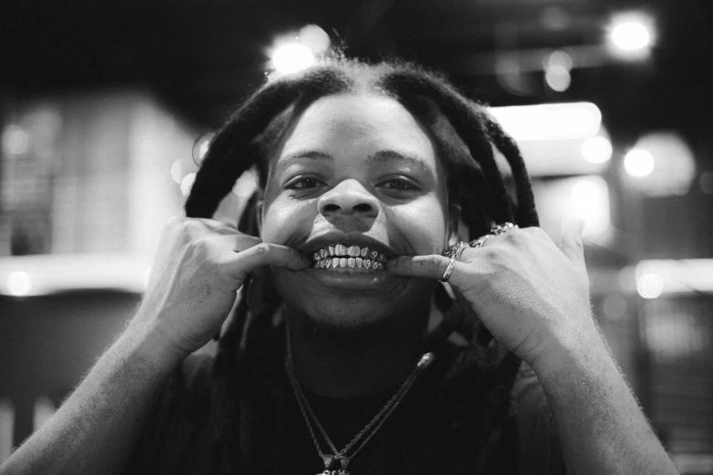 a young person with dreadlocks standing with one hand to his face