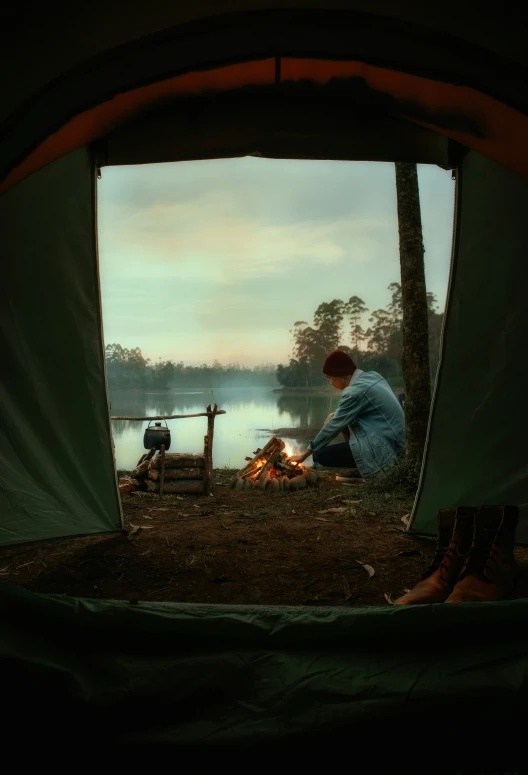 two people in a tent sit around the camp fire