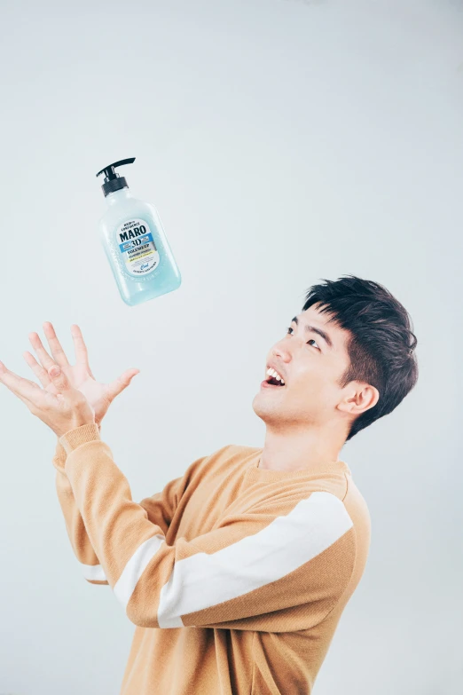 a young man in tan shirt throwing a water bottle