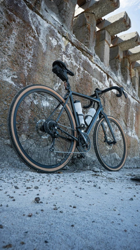 a bike with black and orange frames sits against a stone wall