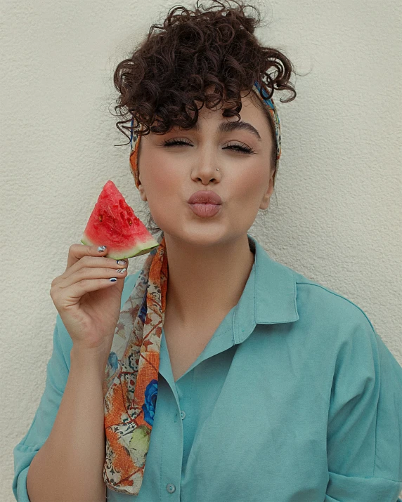 a lady is eating some watermelon with a scarf around her neck