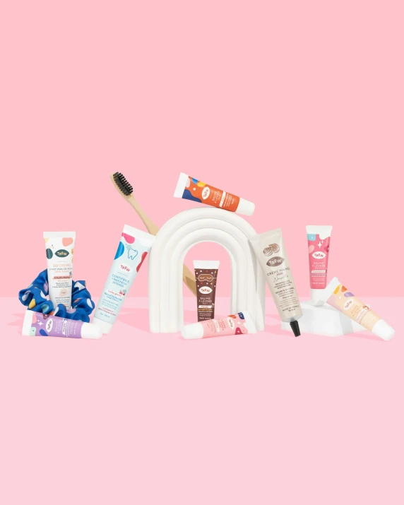 five different beauty products placed on a pink surface