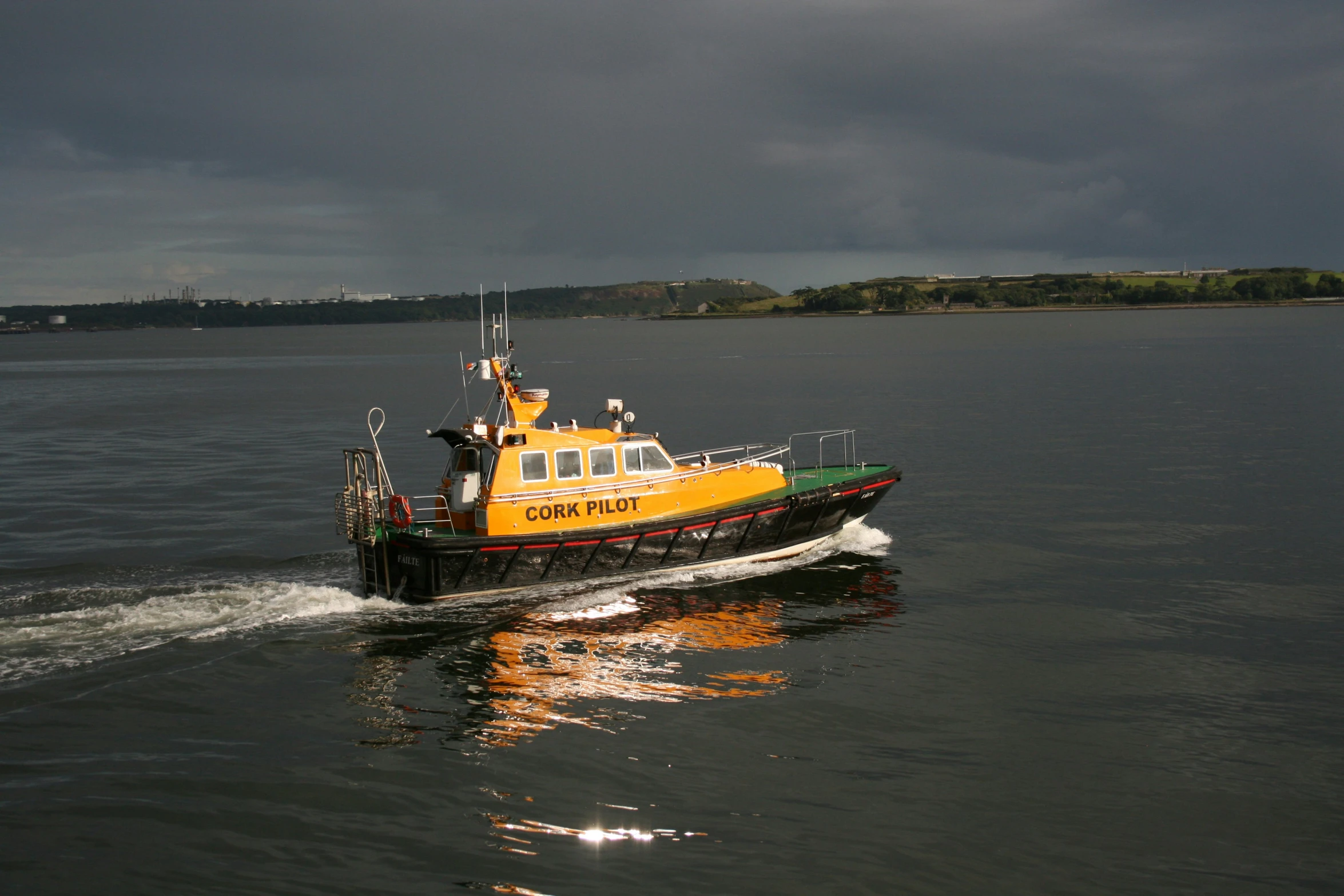 a yellow and black tugboat on water under cloudy skies